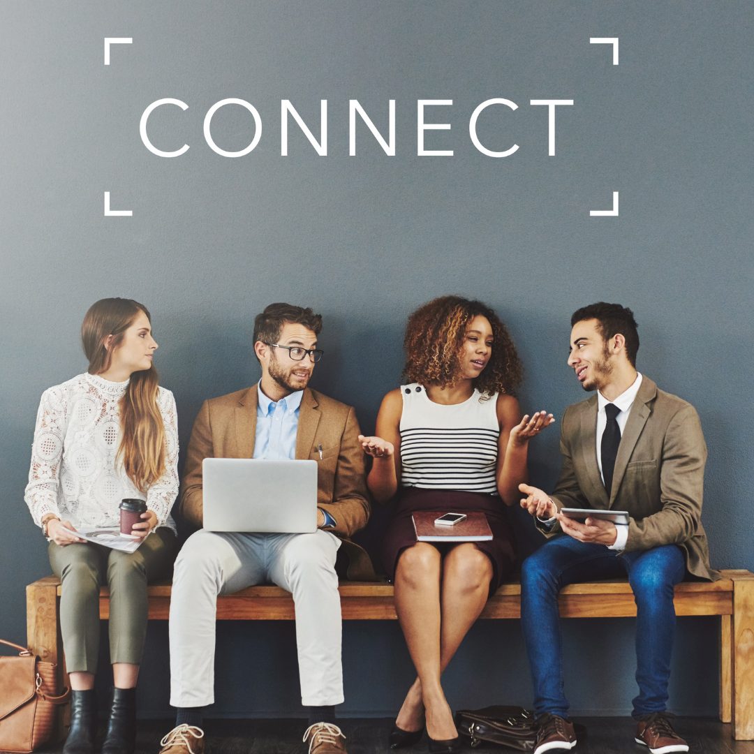 Four diverse young adults sitting on a wooden bench against a blue wall with the word "CONNECT" written above them. They are engaged in conversation, with the second woman from the left gesturing with her hands while speaking, and the others listening attentively. The group appears to be in a casual, professional setting.