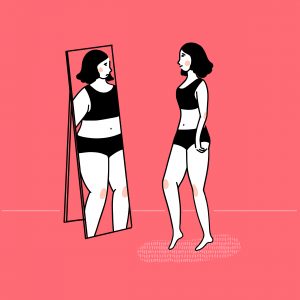 A woman looking at herself in a mirror, standing in a room with a pink background, wearing a black and white striped swimsuit.