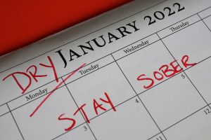 A close-up of a calendar page for January 2022 with the words "DRY JANUARY 2022" written on it, and "STAY SOBER" marked in red.