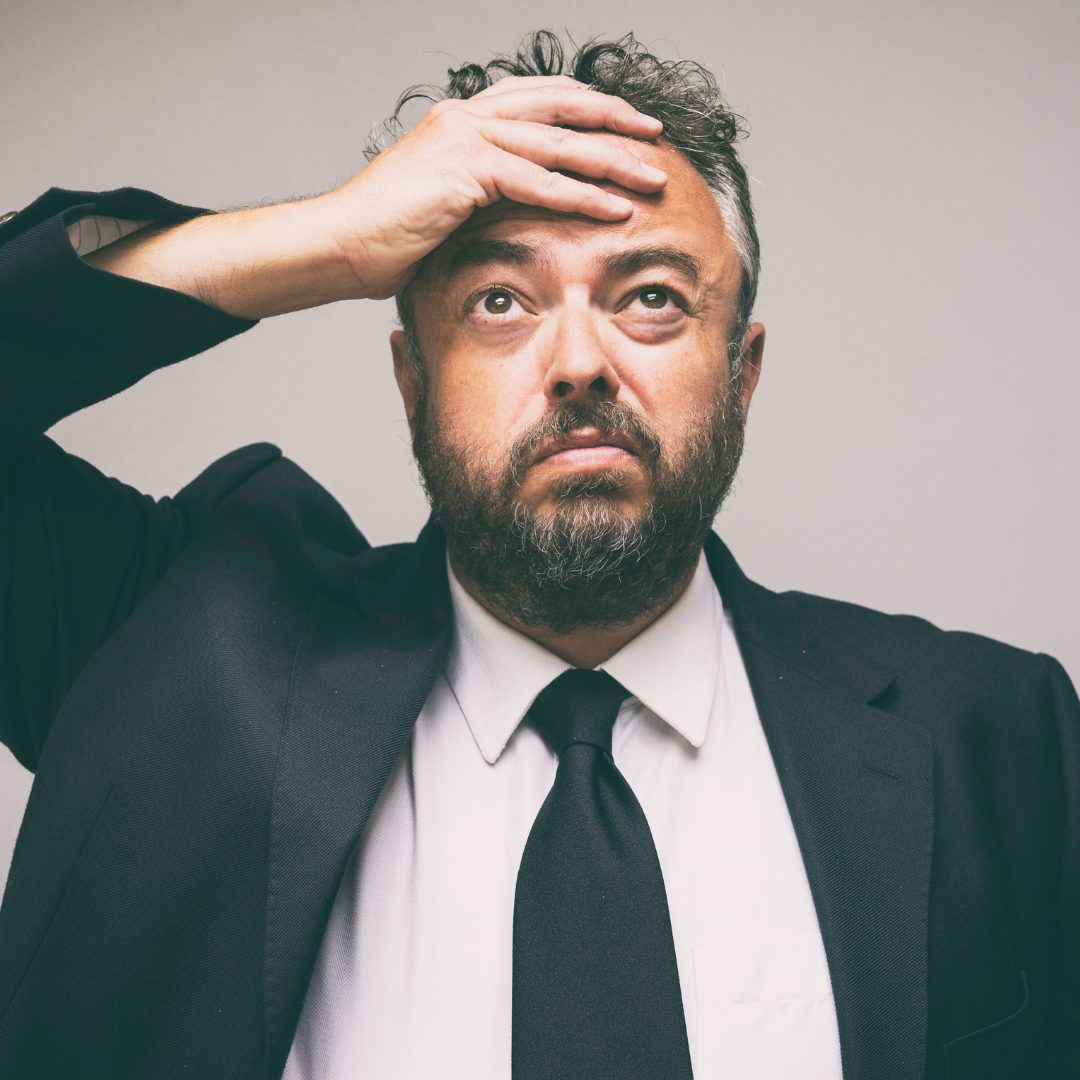 A stressed man with his left hand on his head.