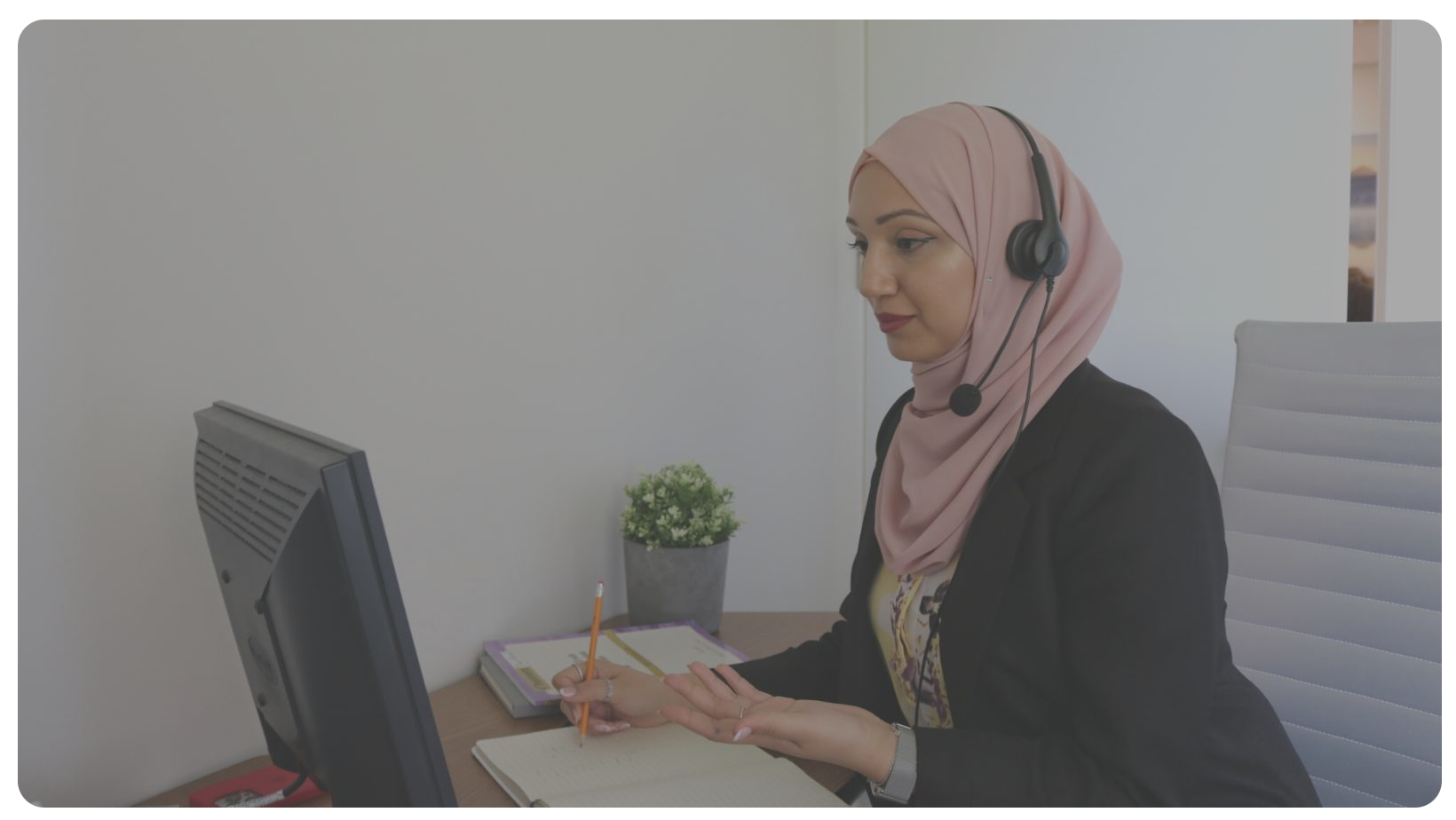 Jumana talking and looking at a laptop, writing, and sitting down.