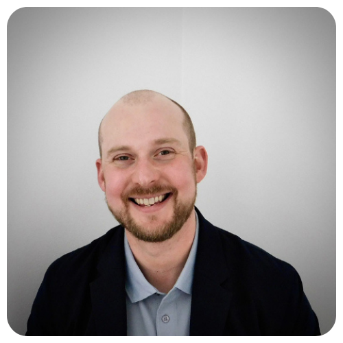 James (Jamie) Melville is smiling, wearing a black jacket over a light blue buttoned shirt.