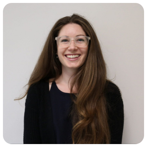 Jenny Stark is smiling, wearing a black sweater with a black tank top.