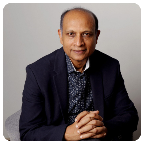 Professional portrait of Dr. Sanjay Rao wearing a dark blazer and patterned shirt, seated with hands clasped, looking calmly at the camera against a neutral background.