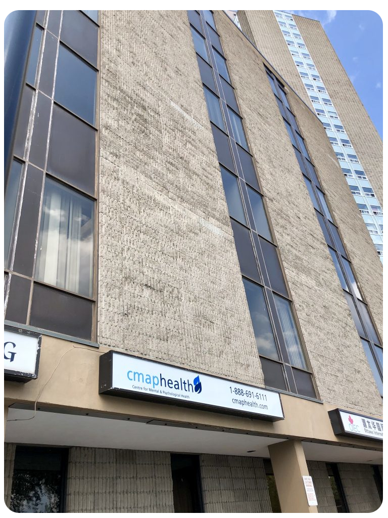 A brown and black building with black windows and a sign that says "Cmap Health" with its contact number next to its logo. A brown and black building with black windows and a sign that says "Cmap Health" with its contact number next to its logo.