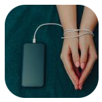 A pair of hands bound together with a white charging cable, connected to a smartphone placed on a teal fabric surface. The person's nails are neatly trimmed and painted with a light pink polish. A pair of hands bound together with a white charging cable, connected to a smartphone placed on a teal fabric surface. The person's nails are neatly trimmed and painted with a light pink polish.
