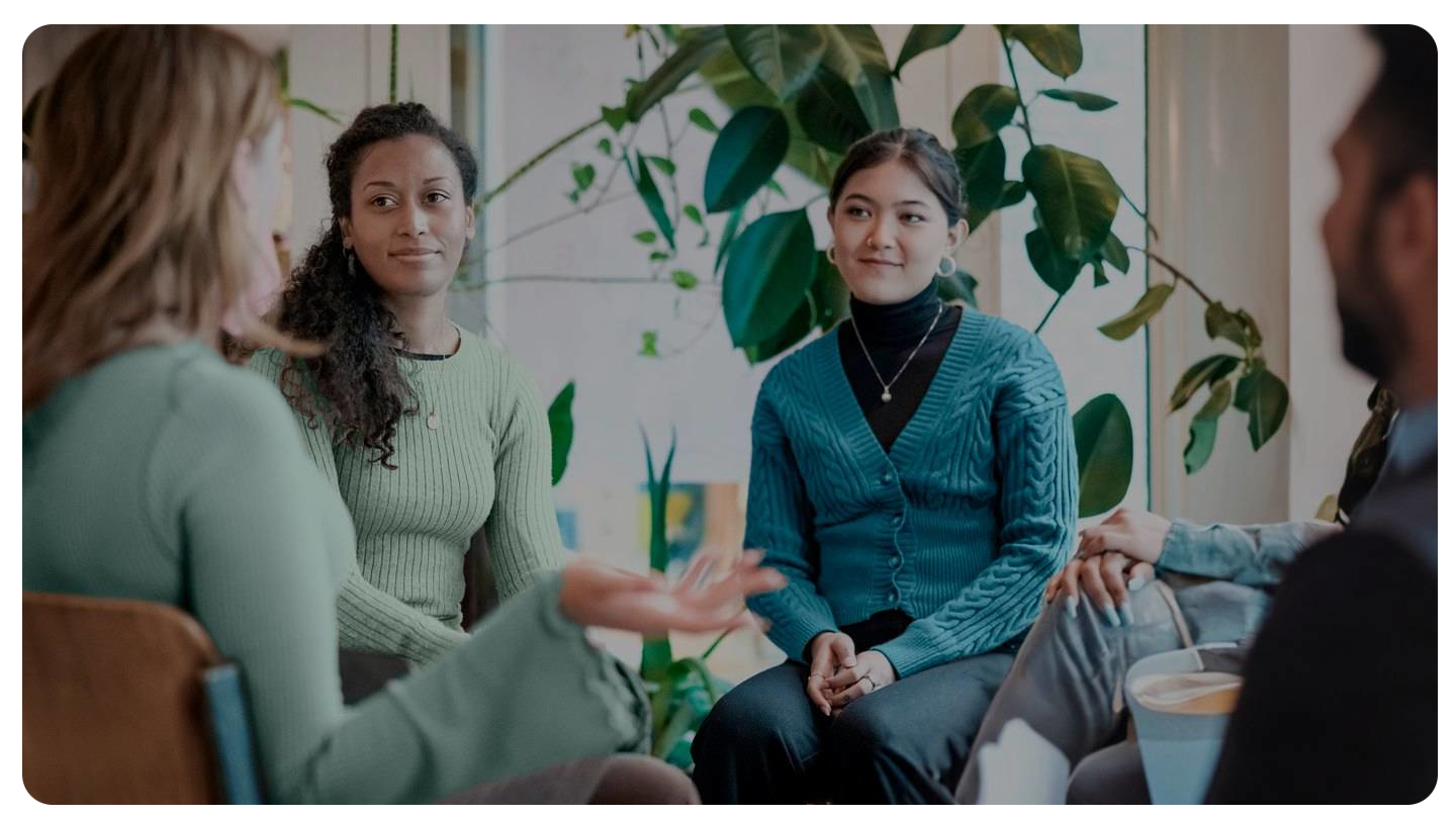 A group of people participating in a therapy session, talking.